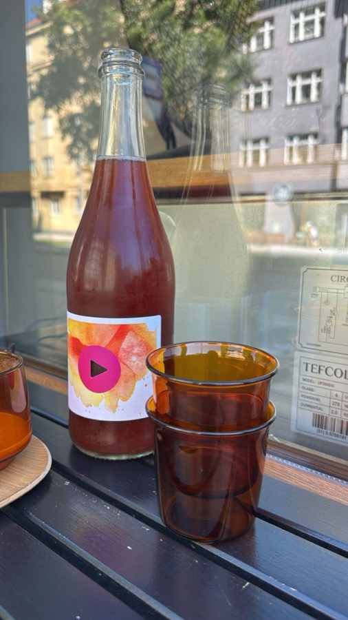 A bottle of cider and amber glasses on a windowsill